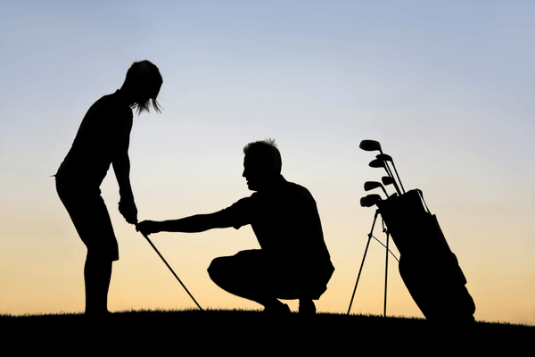 Why Golf Lessons Are Essential for Golfers of Every Skill Level - Silhouette of a golfer and golf instructor against a sunset